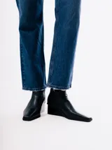 Bota corta de cuero color negro, con taco cuña y puntera cuadrada.
