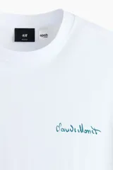 Remera blanca de corte holgado, con cuello redondo y diseño de manga corta. Cuenta con un pequeño estampado tipográfico en color verde en el pecho.