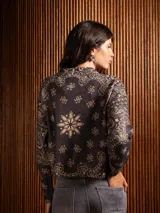 Buzo de punto de manga larga con cuello redondo, confeccionado en un tejido suave de textura peluda. Presenta un diseño estampado con motivos florales y ornamentales en color negro sobre una base de color rojo intenso.