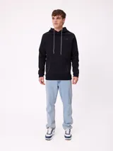 Canguro negro con capucha, cordones ajustables en contraste, bolsillos frontales con cierre y puños acanalados.