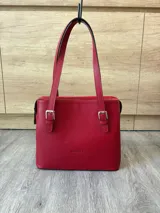 Cartera de hombro estructurada color negro, confeccionada en 100% cuero vacuno con textura en relieve tipo reptil. Cuenta con asas largas ajustables mediante hebillas metálicas plateadas, cierre superior y el logo de la marca grabado en la parte frontal.