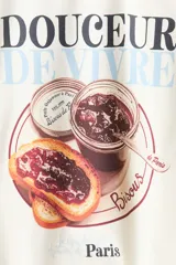 Remera corta de algodón blanca con ribetes celestes en el cuello y las mangas. Presenta un estampado frontal con la inscripción "Douceur de vivre" y una ilustración de tostadas con mermelada y un frasco.
