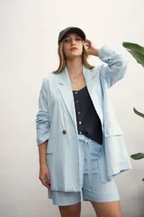 Blazer oversize de lino color celeste claro, de doble botonadura con botones marrones, y bolsillos frontales.