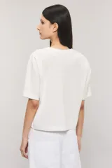 Remera Kosiuko de algodón color blanco, de corte regular y mangas cortas hasta el codo. Cuenta con un diseño estampado en el frente con la leyenda "Messy Chic Kosiuko St. Tropez".