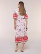 Vestido midi de estilo bohemio en color verde y blanco, con estampa floral, escote en V, cierre frontal con botones, mangas cortas amplias, cintura ajustable con lazo y volado en el bajo.