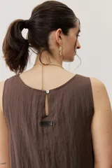 Vestido corto blanco sin mangas, con cuello redondo y detalle de nudo drapeado en el lateral.
