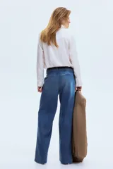 Jean de denim de algodón rígido, color azul con efecto lavado, de tiro alto y corte recto holgado. Cuenta con bolsillos al bies y pliegues marcados al frente y en la espalda.