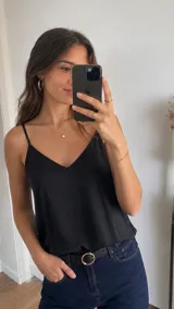 Blusa negra de tirantes finos con escote en V, confeccionada en tejido fluido y suave.