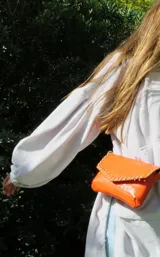 Mini cartera de cuero con diseño texturizado estilo cocodrilo, color naranja, solapa frontal con detalles de costuras entrelazadas y cierre de imán.