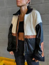 Campera negra con paneles de cuero sintético con textura de cocodrilo, corderito color crema en la parte superior y detalles en cuero marrón.