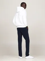 Buzo con capucha y cordón ajustable Tommy Hilfiger, color blanco, de corte regular. Presenta un bolsillo estilo canguro en la parte delantera y una franja horizontal en el pecho con el logotipo y los colores distintivos de la marca.