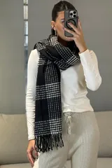 Bufanda rectangular con diseño de cuadros escoceses en blanco y negro, con flecos en los extremos.