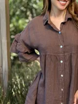 Vestido camisero blanco de lino italiano, con cuello camisero, cierre frontal con botones, mangas cortas con doble volado y bolsillos laterales.