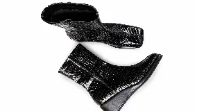 Bota de caña media con punta cuadrada y cierre lateral, confeccionada en cuero con textura croco y acabado charol negro.