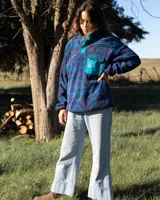 Buzo de polar fleece con diseño estampado geométrico en tonos azules, bordó y verde. Presenta cuello alto con cierre de botones a presión, bolsillo frontal con solapa en contraste color turquesa y puños elásticos.