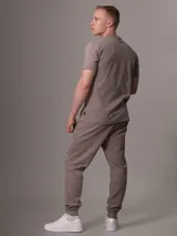 Pantalón de jogging color topo, con cintura elástica ajustable con cordón, puños ajustados y bolsillos laterales con cierre.
