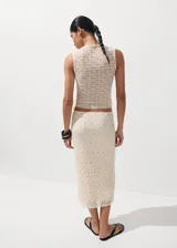 Falda midi de corte recto, confeccionada en tejido texturizado de color beige con pequeñas tachas metálicas distribuidas en el diseño y forro interior.