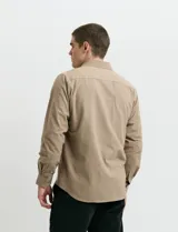 Camisa de franela lisa con cuello button-down, manga larga, botones al tono y bolsillo frontal en el pecho.
