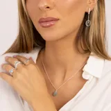 Aros colgantes de plata 925 con tres pequeñas piedras de la luna y una piedra de topacio azul ovalada.