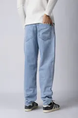 Jean de corte mom oversize, color negro lavado, con diseño de cinco bolsillos y cierre frontal con botón y cremallera.