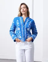 Chaqueta de algodón bordada, color azul con bordado floral blanco, con cuello a la base y escote en V, abertura central con botón.