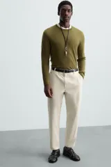 Pantalón chino de algodón color crema, corte regular fit, con cierre frontal de cremallera y botón, bolsillos delanteros y bolsillos traseros de vivo con botón.