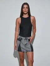 Minifalda de denim en color gris oscuro con diseño de paneles en contraste de lavado, tiro medio y cierre frontal con botón y cremallera.