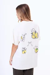 Remera de algodón color blanco, de corte holgado y manga corta, con estampado gráfico en la espalda que incluye dibujos de limones, una jarra, un vaso y un lazo.