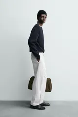 Pantalón chino de corte oversized confeccionado en tejido de algodón con estructura twill. Presenta bolsillos frontales, bolsillos traseros de vivo y cierre frontal con cremallera y gancho metálico oculto.