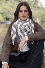 Bufanda triangular de tejido de punto con diseño de rayas diagonales en tonos gris y beige.