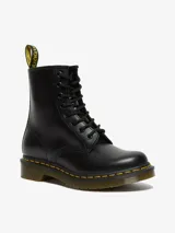Botas de caña media Dr. Martens modelo 1460, color negro con acabado liso. Presentan cierre de cordones con 8 ojales, suela de goma acanalada con cámara de aire, pespuntes amarillos característicos y tirador de talón con logo.