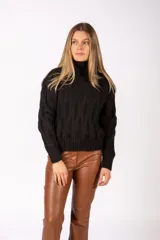 Sweater de punto negro con cuello alto y diseño de trenzas verticales. Presenta puños y ruedo acanalados.
