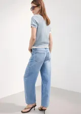 Jeans de mezclilla color celeste claro, de corte recto y tiro medio con diseño clásico de cinco bolsillos y cierre frontal con botón y cremallera.