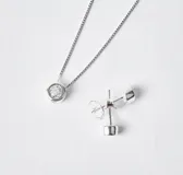 Set de joyería compuesto por collar con dije de punto de luz y par de caravanas a juego, confeccionados en plata 925 con engaste de circonias.