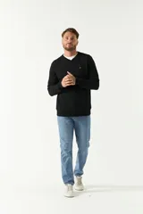 Sweater de punto color negro con escote en V, manga larga y puños acanalados. Presenta un pequeño logo bordado en el pecho.
