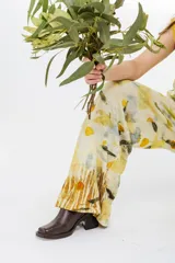 Pantalón de pierna ancha con estampado de hojas en tonos amarillos y marrones, cintura elastizada y bolsillos laterales.