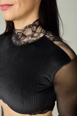 Conjunto de lencería negro compuesto por un top corto de terciopelo con cuello alto y mangas largas de microtul transparente con detalles de encaje, y una tanga regulable a juego con detalles de encaje y microtul.