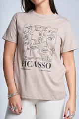 Remera de algodón color beige con estampado frontal de arte lineal inspirado en Picasso y texto alusivo al museo de Barcelona.