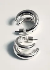 Aros de metal plateado con diseño tubular doble, estilo argolla con cierre a presión.