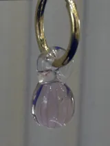 Aros tipo argolla dorada con dije colgante de vidrio soplado en forma de lágrima estriada de color rosado traslúcido.