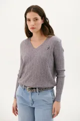 Sweater gris de punto con escote en V, tejido en ochos y bordado pequeño en el pecho.