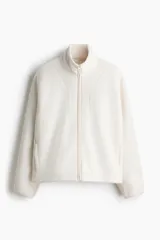 Campera deportiva de sherpa en color blanco, de corte holgado, con cuello elevado, cierre frontal y bolsillos laterales.
