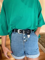 Cinturón negro de cuero con hebilla metálica plateada de estilo western.