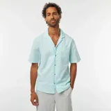 Camisa celeste de lino con cuello cubano, manga corta, cierre con botones y bolsillo en el pecho.