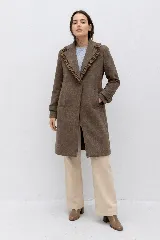 Tapado de lana color marrón con silueta entallada, solapas clásicas decoradas con volados en contraste y cierre frontal oculto.