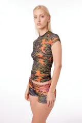 Remera anatómica de manga corta, confeccionada en tejido de poliéster con estampado de tigresa en tonos verde, naranja y negro.
