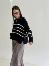 Sweater estilo chomba con cierre frontal, confeccionado en tejido bremer rayado de manga larga. Presenta un diseño amplio y moderno con cuello polo.