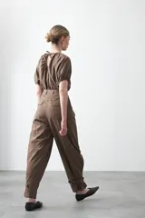 Pantalón baggy negro de silueta relajada con volumen amplio y caída fluida. Presenta detalles de ajuste con hebillas metálicas en el bajo y un cinturón de tela con hebilla metálica en la cintura.