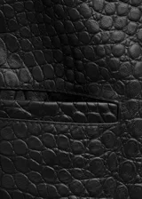 Chaqueta corta de cuero negro con textura efecto cocodrilo, diseño recto, cuello camisero, manga larga, bolsillos laterales de ribete y cierre de doble botonadura.