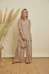 Conjunto de dos piezas color beige, compuesto por una blusa holgada de manga 3/4 con escote en V y detalles de lentejuelas, y un pantalón palazzo con aberturas laterales.